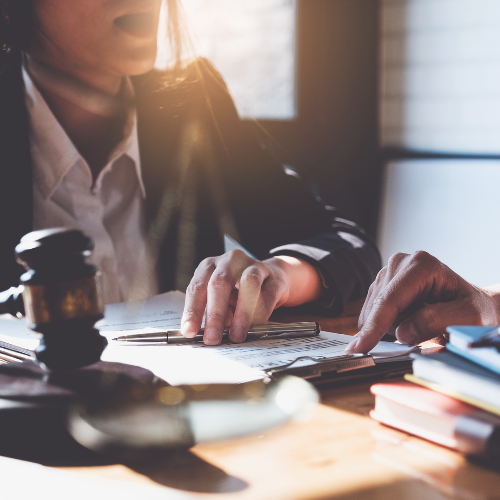 A lawyer sitting behind a table with documents and books and a gavel